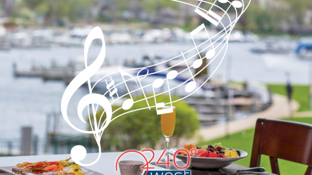 A table with plates of food overlooks a waterfront. Musical notes are superimposed. The logo 