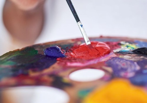 Someone is mixing vibrant paint colors on a palette using a brush, likely preparing to create a colorful artwork.