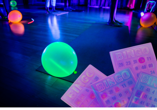 The image shows glowing balloons, bingo cards, and an illuminated scene likely from a glow-themed event or party.