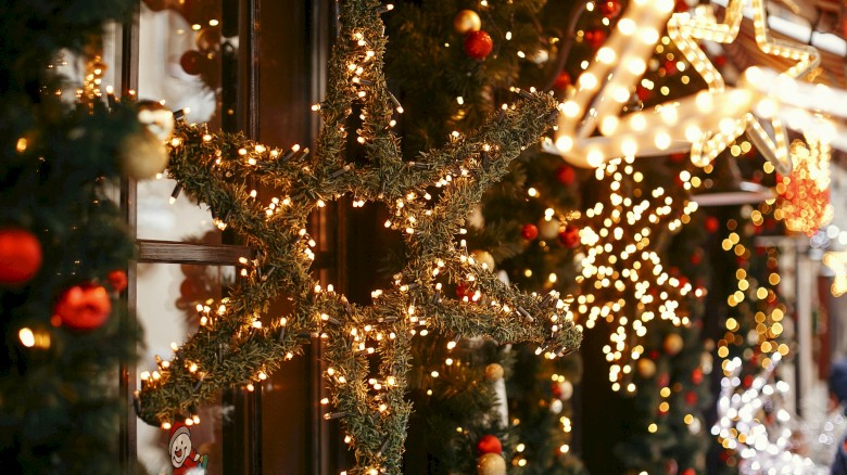 Christmas decorations with lights, stars, and ornaments on a festive street at night.