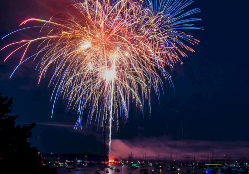 Colorful fireworks light up the night sky over a harbor filled with boats.