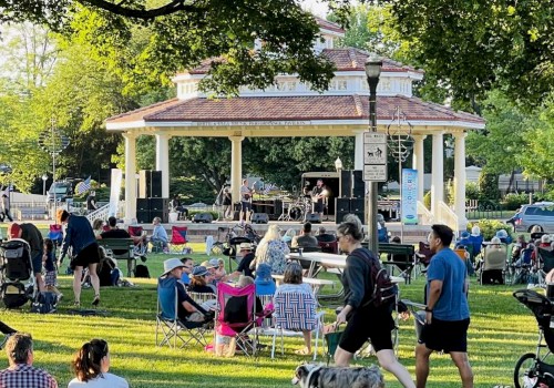 A lively outdoor concert in a park with families, children, and musicians enjoying a sunny afternoon under green trees.
