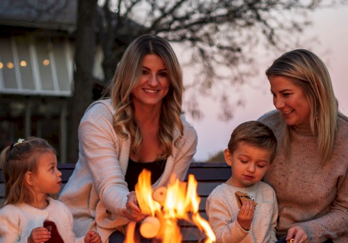 A family gathers around a firepit outdoors during sunset, enjoying snacks and smiles on a cozy evening.