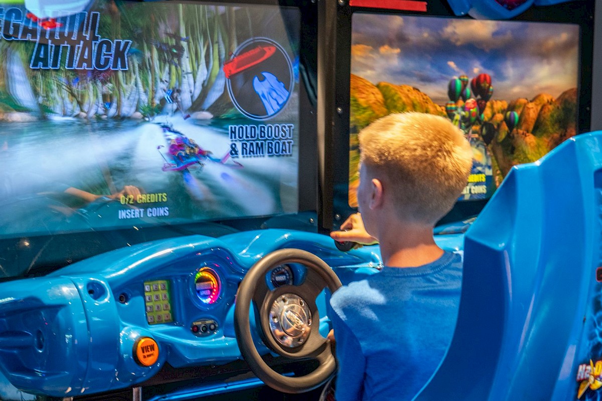 A boy with blonde hair is playing an arcade racing game called 