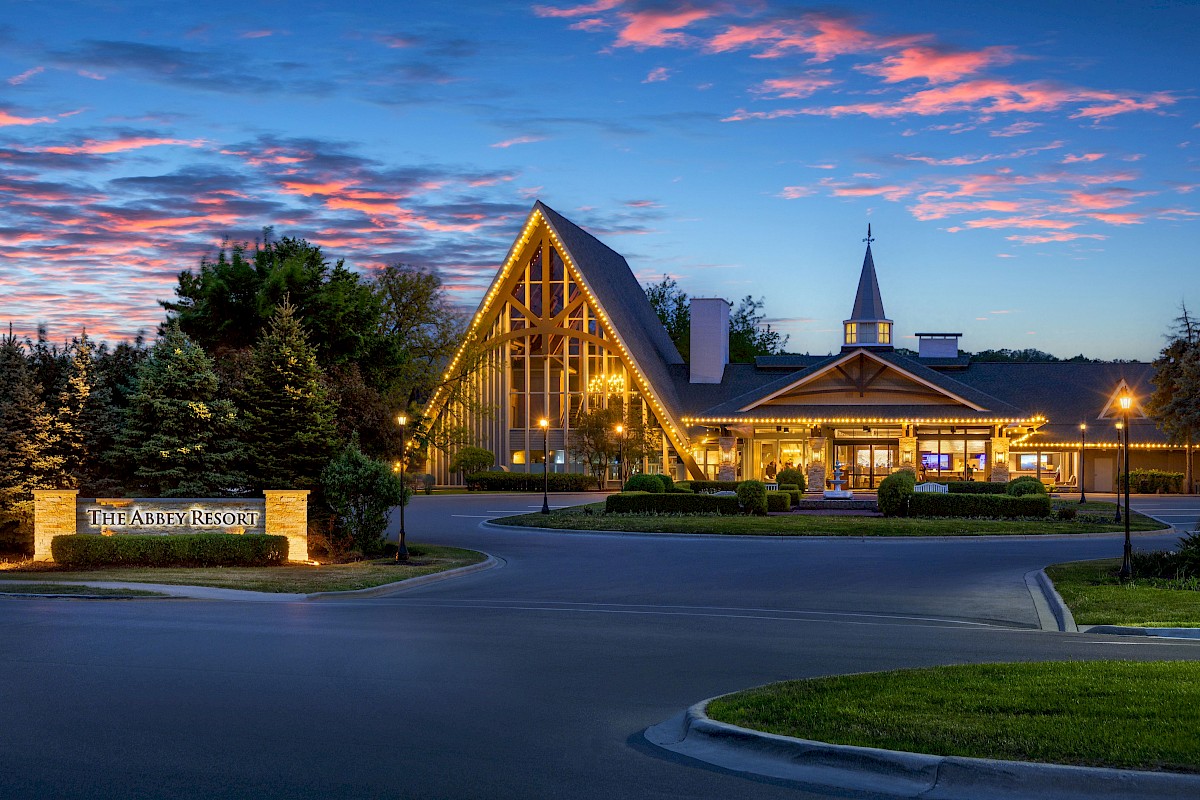 This is an image of The Abbey Resort, a beautifully lit building with trees and streetlights at dusk, showcasing a peaceful, inviting atmosphere.