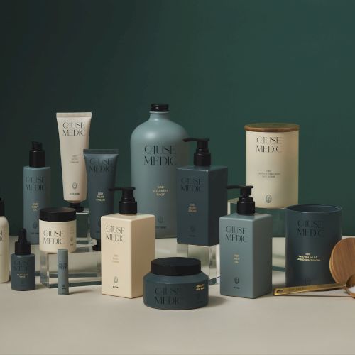 The image shows a collection of skincare and personal care products, including creams, lotions, and bottles, displayed on a surface against a green background.