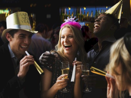 A lively birthday party: people in party hats laughing and chatting, cups and noise makers in hand, festive mood and confetti ready.