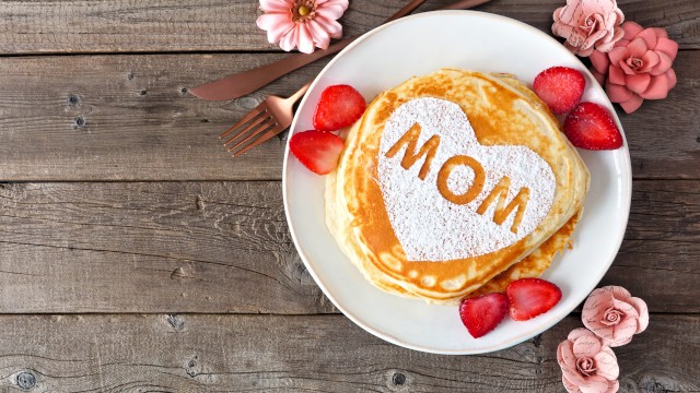 A stack of pancakes with a heart-shaped powder sugar design and the word 