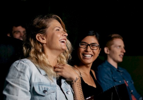 Three people are sitting and laughing, likely enjoying a movie or performance together.