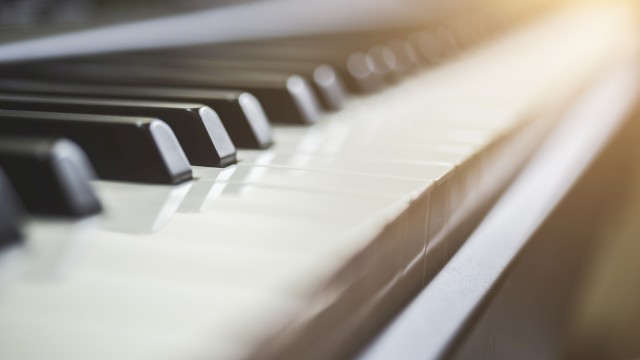 A close-up of piano keys with soft lighting highlighting the keys from the upper right corner, creating a warm and inviting atmosphere.