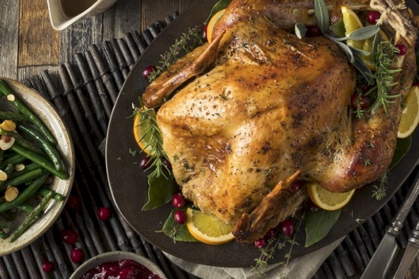 A table set with a roasted turkey, gravy, brussels sprouts, green beans, cranberry sauce, mashed potatoes, and other dishes.