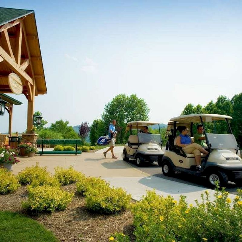 The image shows a golf clubhouse with people and golf carts outside. There are two men driving carts and one walking with golf bags in the background.
